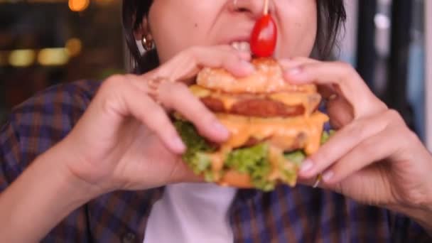 Fiatal vonzó vegyes fajú lány eszik növényi alapú burger étteremben. A nő leharap egy ízletes szájvizet adó hamburgert, kiváló minőségű 4K lassított felvételeket. Bangkok, Thaiföld. — Stock videók