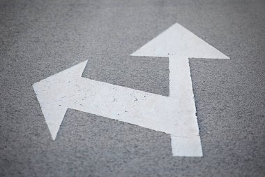 Yol üzerinde beyaz oklarla işaretlenmiş trafik levhası