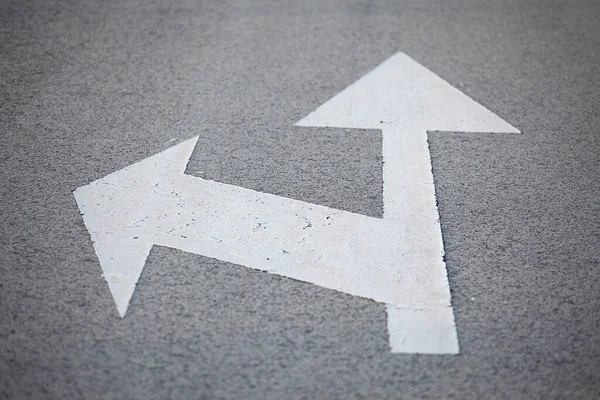 Traffic sign painted on the road with direction arrows in white