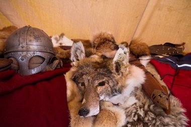 Bir köy panayırında, Viking kaskı ve kılıcının yanında kırmızı bir pelerinin üzerine uzanmış tilki kürkünün kapağını kapatın..