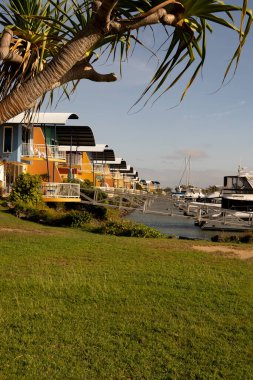 Keppel Bay Marina, Rosslyn Bay, Yeppoon 'da demirli, parlak renkli lüks villalar. Dikey biçim.