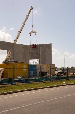 İnşaat alanı, vinç kaldırdıktan sonra işçilerin vinç söktüğü beton temellere eğimli prefabrik beton paneller kullanılarak inşa ediliyor..