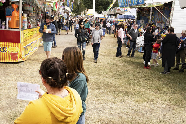 Crowds of people in side show alley at a small regional agricultural show or fair at Finch Hatton, Queensland, Australia.