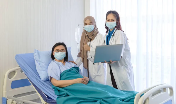 청진기 압력을 사용하는 회교도 의사와 아시아 의사가 노트북을 침대에 환자에게 — 스톡 사진