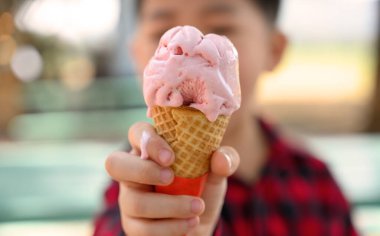 Asyalı çocuğun elinde tatlı çilekli dondurma, mutlu çocukluk konsepti, 6 yaşındaki çocuk dondurmasının tadını çıkarsın.