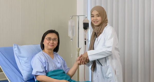 Dokter Wanita Muslim Memegang Tangan Pasien Tua Duduk Tempat Tidur — Stok Foto