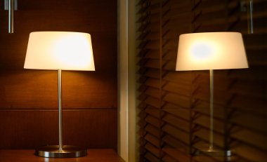 Lamba ya da fener, yatağın yanındaki ahşap masada yansıtıcı camla parlıyordu.