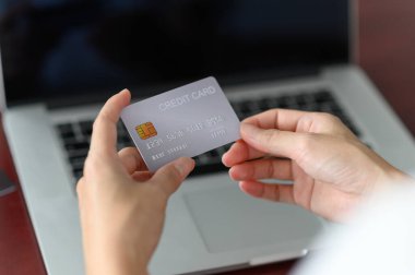 Elinde dizüstü bilgisayarı olan kredi kartı tutan bir kadın. Kredi kartıyla ödeme, online alışveriş konsepti