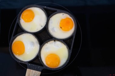 Kahvaltı için elektrikli ocağın üstünde sahanda yumurta yapma manzarası.