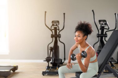 Sporty fitness African American woman working out with dumbbells strength and strength endurance at the gym