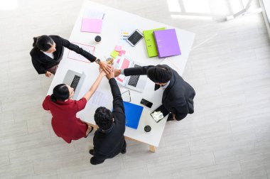 İş adamlarının masanın üzerinde el çırpışları, masanın altına yerleştirilmiş grafikler. Genç işadamı ve iş kadını el birliği ve takım çalışması desteği gösteriyor