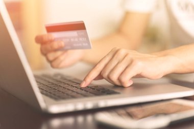 Kredi kartı tutan ve internetten bilgisayar alışverişi yapan kadınların ellerini kapat. E-ticaret, internet bankacılığı, kontrol bakiyesi, bankacılık hizmeti, kredi kartıyla ödeme, ödeme