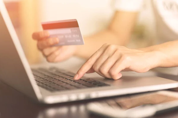 Close up woman hands holding credit card and using laptop shopping purchasing online. e-commerce, internet banking, checking balance, banking service, paying by credit card, making payment