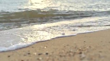 Close up soft wave water on sandy beach seaside during sunset. summer vacation activity background concept