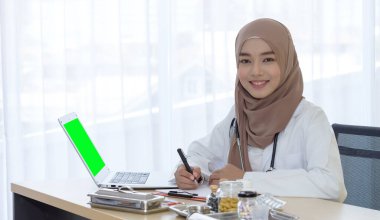 Güzel genç Müslüman kadın doktor gülümse ve kameraya bak elinde kalem, hastane ofisi, tıp ve sağlık hizmetleri konseptine not al