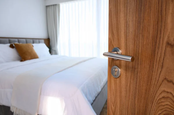wooden door open to modern bedroom. selective focus to door handle, bedroom blurred on background. Hotel room, Condominium, or apartment doorway