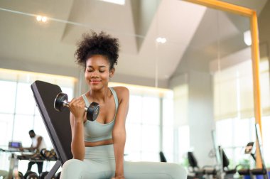 Sporty fitness African American woman working out with dumbbells strength and strength endurance at the gym