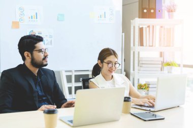 Ofisteki dizüstü bilgisayarlarla birlikte çalışan iş adamları, iş kadını ve işadamı dizüstü bilgisayardaki belgeleri kontrol ediyorlar.