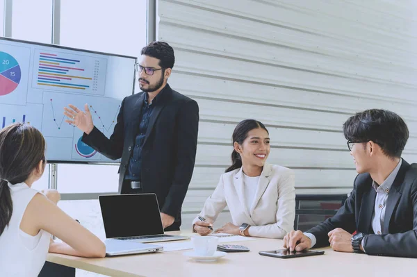 Businessman Giving Presentation Report to Business Team in the Conference Room, Shows Digital Information Graphics, Pie Charts about Company Growth on TV