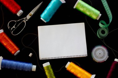 Siyah arka plandaki notlar için dikiş malzemeleri ve not defteri. Metin için yer