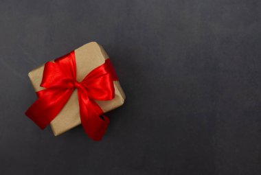 The concept of celebrating different holidays. Gift box with red bow on a black background. Copy space. Celebrating Valentine's Day, Mother's Day, Christmas, Birthday.