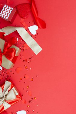 Preparation and celebration of Valentine's Day. Creative composition with gifts, ribbons and hearts on a red background. Copy space.