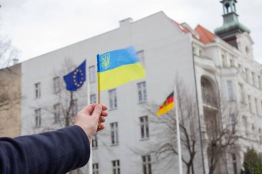 WROCLAW, POLAND - 19 Şubat 2022: Ukrayna bayrağını Avrupa Birliği ve Almanya Federal Cumhuriyeti 'nin bayraklarına karşı tutan adam. Ukrayna 'da barışı desteklemek için toplantı