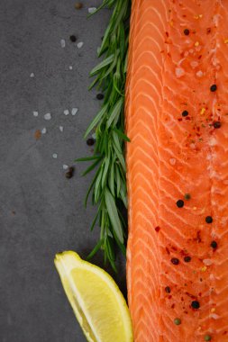 Fresh salmon with rosemary and spices on a black background. Fresh fish.