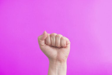Female fist on a pink background. The concept of feminism and the struggle for womens rights. Girl power.