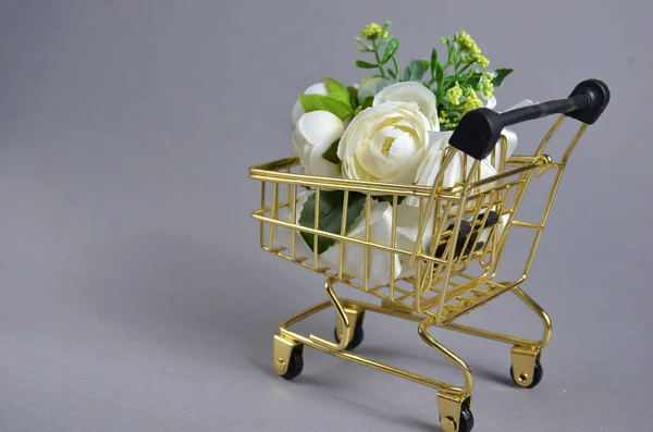 Λευκά τριαντάφυλλα σε καρότσι για ψώνια. Γκρι φόντο. — Φωτογραφία Αρχείου