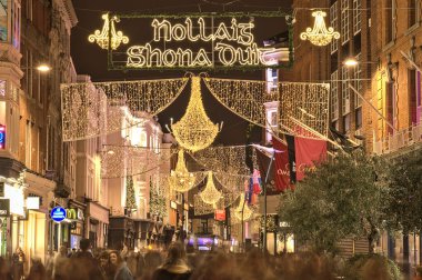 Dublin, İrlanda - 13 Kasım. 2021: Nollaig shona dhuit Noel ışıklarının güzel akşam manzarası. Grafton Caddesi 'nde İrlandaca yazılmış Mutlu Noeller tabelası. Kalabalık cadde