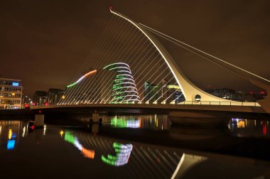 Dublin, İrlanda - 13 Kasım 2021: Samuel Beckett Köprüsü ve Dublin Kongre Merkezi 'nin İrlanda bayrağı ve su yansımasını taklit eden halka kirişli güzel geniş açılı akşam manzarası