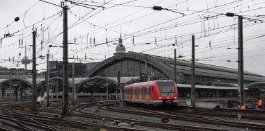 Köln, Almanya - 25 Şubat 2022 Deutsche Bahn 'in kırmızı treni Köln' ün ana istasyonundan kalkıyor. Arka planda göçmen bürosu gitmeye hazır.