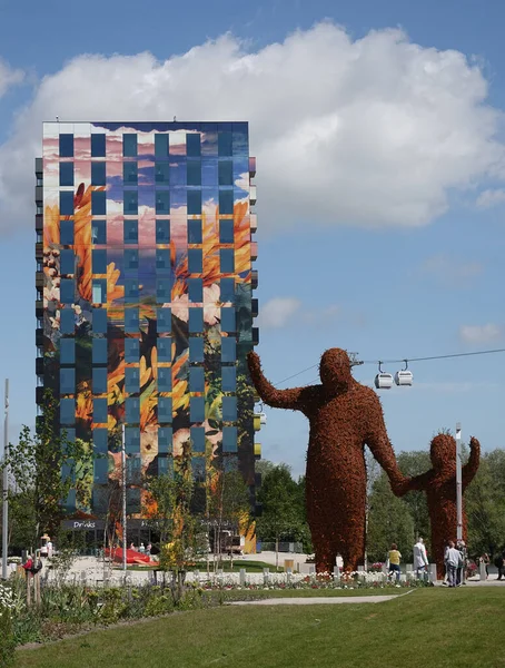 Almere, Hollanda - 11 Mayıs 2022 Floriade Fuarı - Fuarın iki göz alıcısı bir fotoğrafta. Florentijn Hofman 'ın Beehold adlı dev heykeli ve gelecekte Flores adında 14 katlı bir konut binası..   