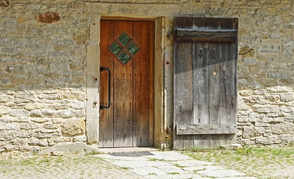 A very old door with glass panels and a large iron grip. The door has a second door which can be closed too.