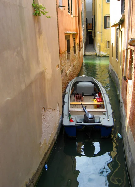 Very narrow residential canal in Venice, Italy. A motor boat just fits in