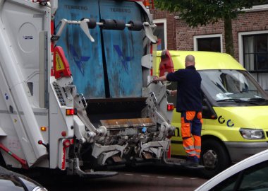 Leiden, Hollanda - 8 Temmuz 2016 Hollandalı bir çöpçü çöp kamyonunun arkasında duruyor