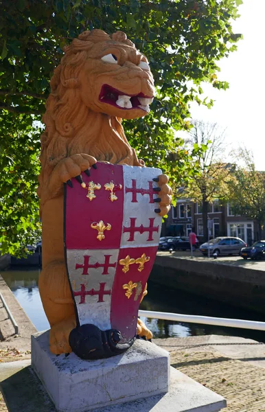 Three centuries old lion standing at the corner of the Lions bridge in Harlingen,  the Netherlands. He carries the coat of arms of his town