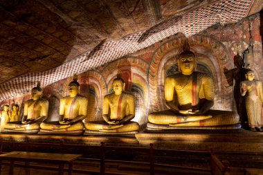Sri Lanka. Dambulla Mağara Tapınağı. Sıraya dizilmiş Buda heykelleri, aşağıdaki lambalarla aydınlatılıyor..