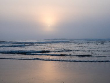 Kuzey Jetty sahilindeki yoğun siste Pasifik Okyanusu 'na batan Güneş Okyanus Kıyıları, WA, ABD