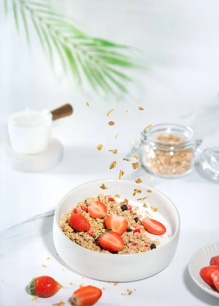 Egy tál granola joghurttal, tejjel és friss málnával, áfonyával, mangóval egy egészséges reggeliért egy fehér márványasztalon — Stock Fotó