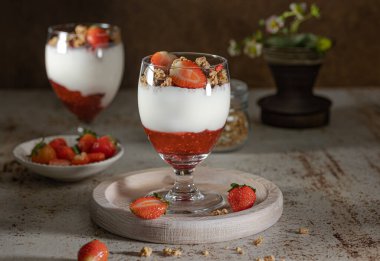 Yoğurtlu granola, süt ve taze ahududu, yabanmersini, mango ve koyu arkaplanda sağlıklı bir kahvaltı.