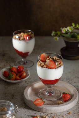 Yoğurtlu granola, süt ve taze ahududu, yabanmersini, mango ve koyu arkaplanda sağlıklı bir kahvaltı.