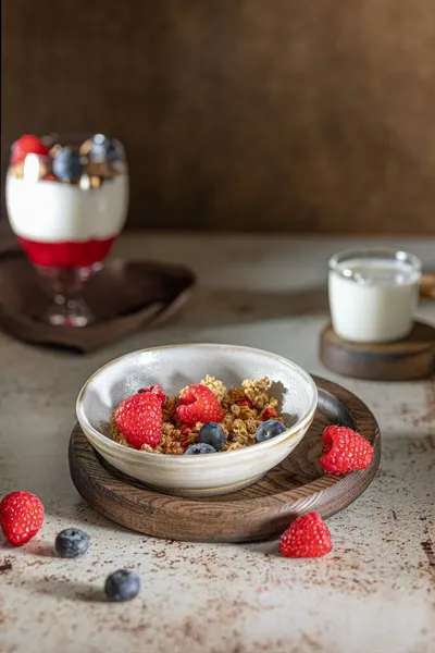 Egy tál müzli joghurttal, tejjel és friss málnával, áfonyával, mangóval az egészséges reggeliért a sötét háttérben — Stock Fotó