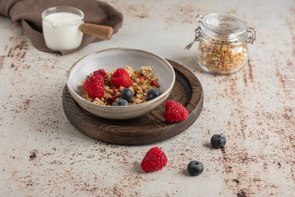Bowl of granola with yogurt, milk and fresh raspberries, blueberries, mango for a healthy breakfast on the dark background — Stock Photo, Image