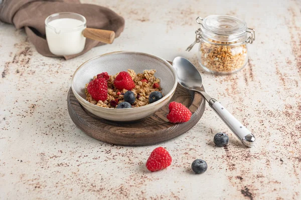 Bowl of granola with yogurt, milk and fresh raspberries, blueberries, mango for a healthy breakfast on the dark background — Stock Photo, Image