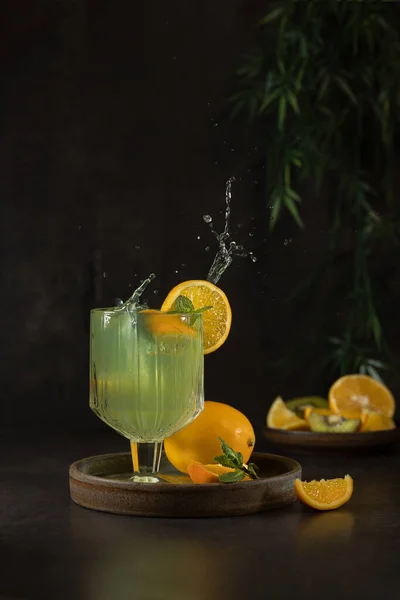 Glasses with lemonade or mojito cocktail with lemon orange and mint, a cold refreshing drink on a dark background. — Stock Photo, Image