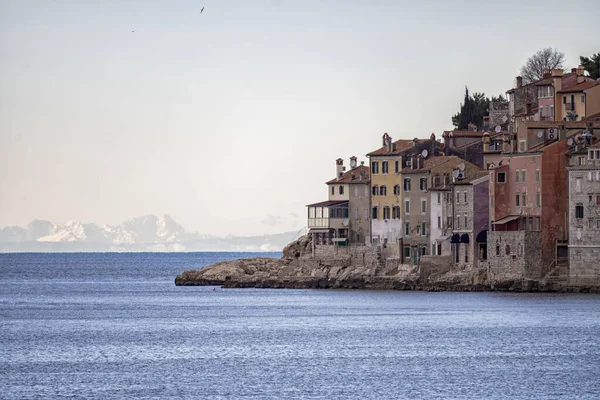 Rovinj, Hırvatistan-6 Ocak 2022: Adriyatik 'in Rovinj kasabasının güzel ve yoğun binaları, denizin karşısındaki zar zor görülen İtalyan Alplerine karşı tanınan renkli cephelerle inşa edildi