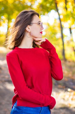 Doğada kırmızı kazaklı bir kız. Kırmızılı kız. Kırmızı dudaklı kız. Sonbahar fotoğrafı
