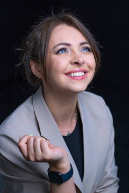 Gülümseyen güzel bir kadın portresi. Siyah arka planda gri takım elbiseli güzel kadın.